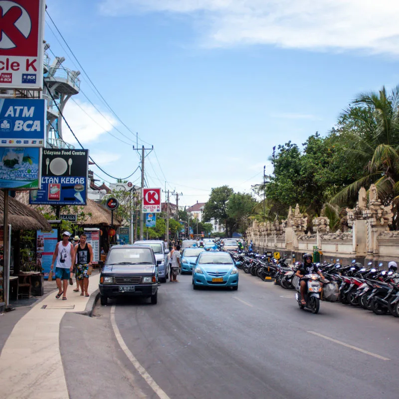Taxis-Drive-Down-Road-In-Central-Kuta-Bali