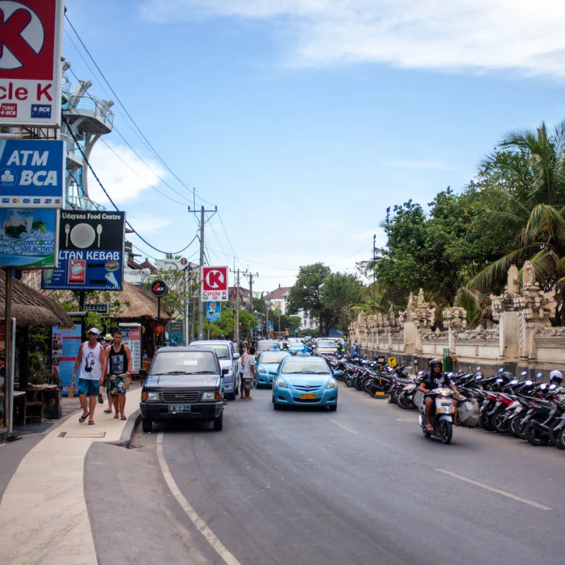 Taxis Drive Down Road In Central Kuta Bali