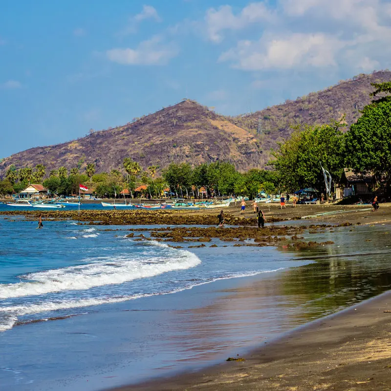 Tourists Explore Black Sand Beach In Buleleng North Bali