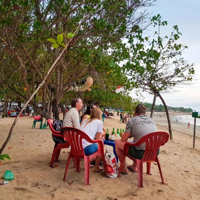 Tourists Relax And Drink Beers On Kuta Beach In Bali