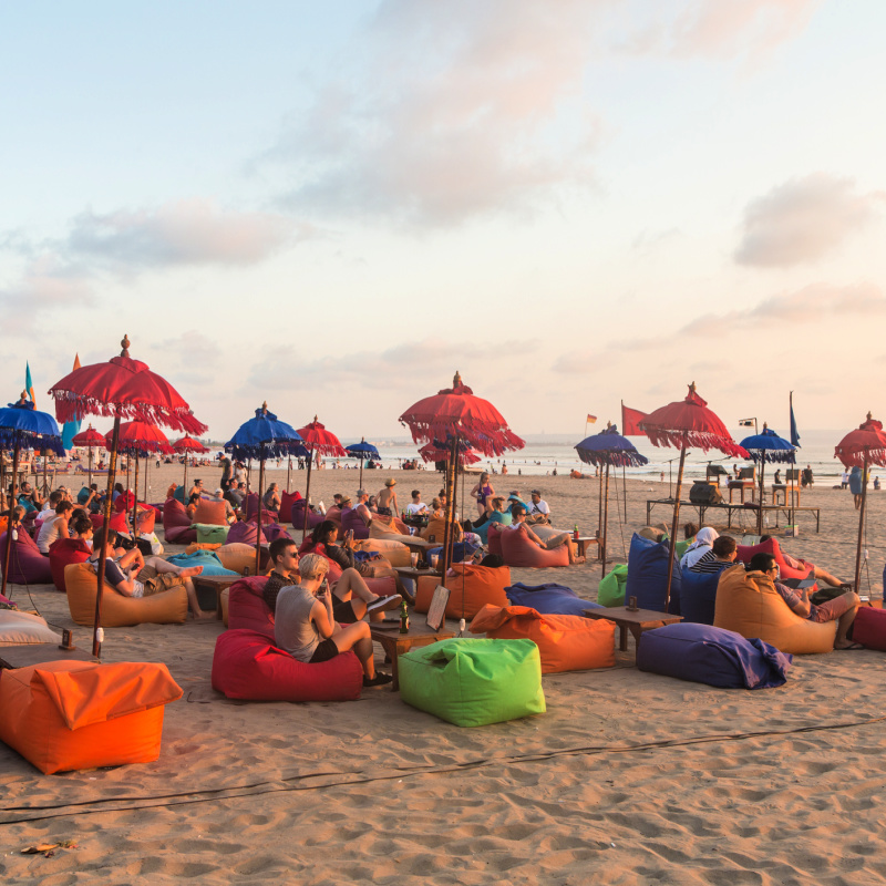 Tourists Relax On Bali Beach At Sunset 