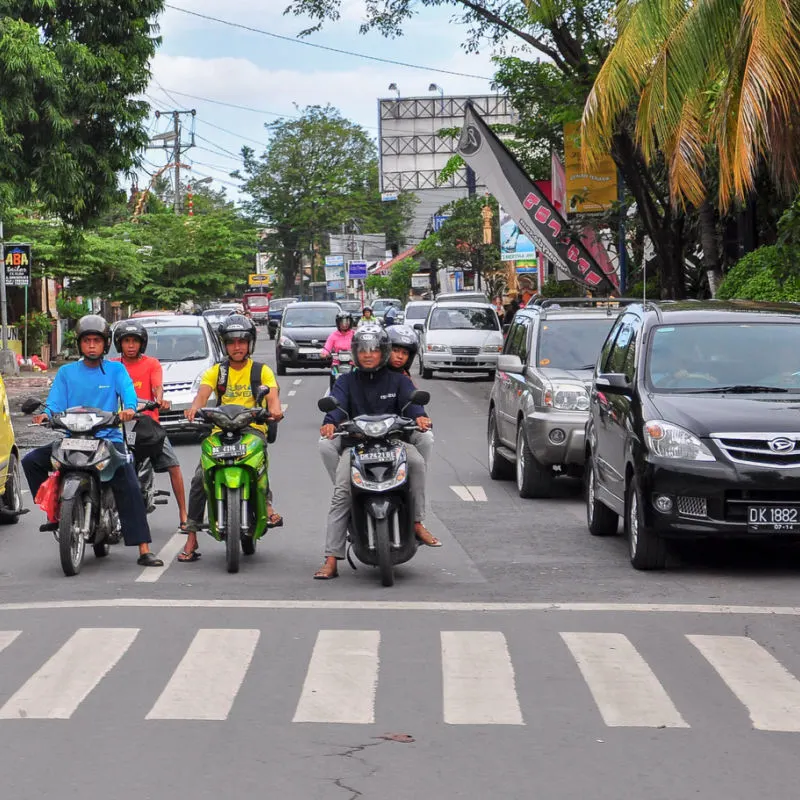 Traffic Mopeds And Car Wait At Zebra Crossing On Road In Bali