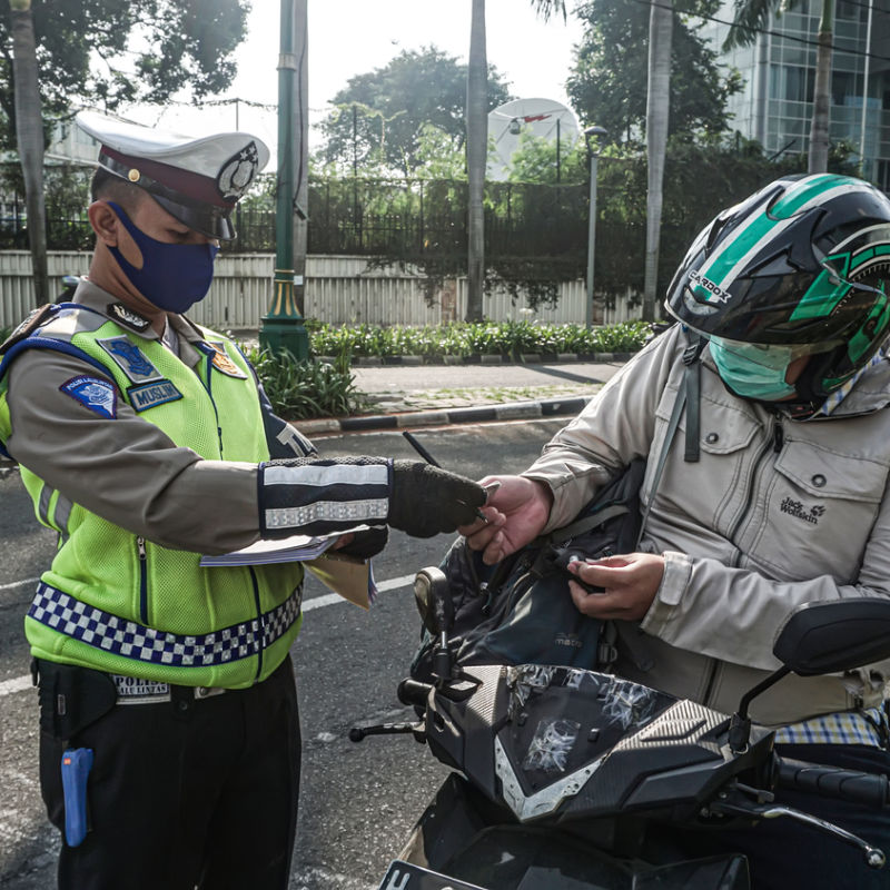 Traffic Police Officer Checks The ID Of A Driver In Bali.