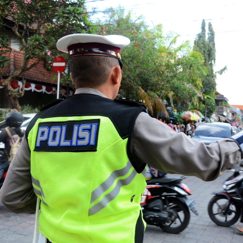 Traffic Police Officer Directs Mopeds And Cars On A Road In Bali