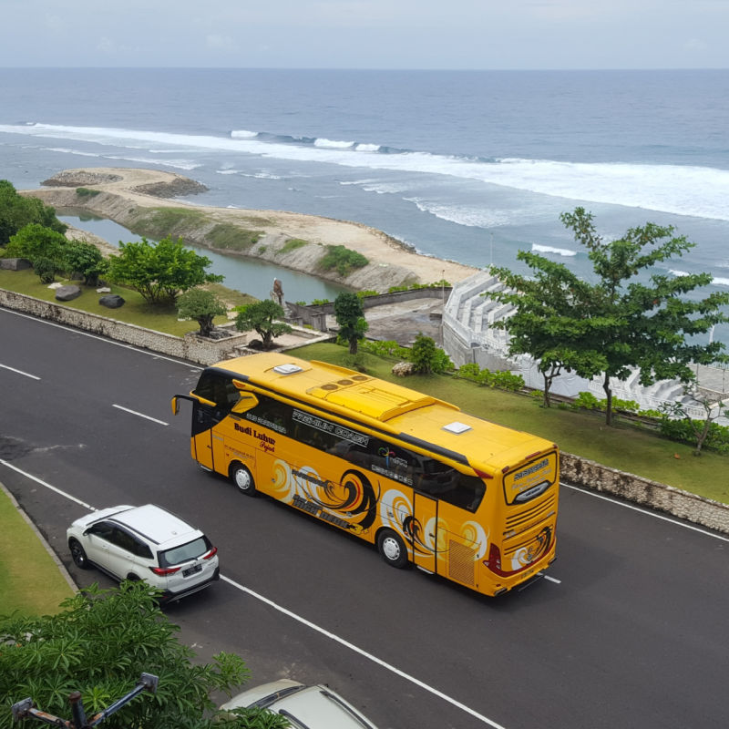 Yellow Bus Drives On Bali Road In Kuta area by the sea