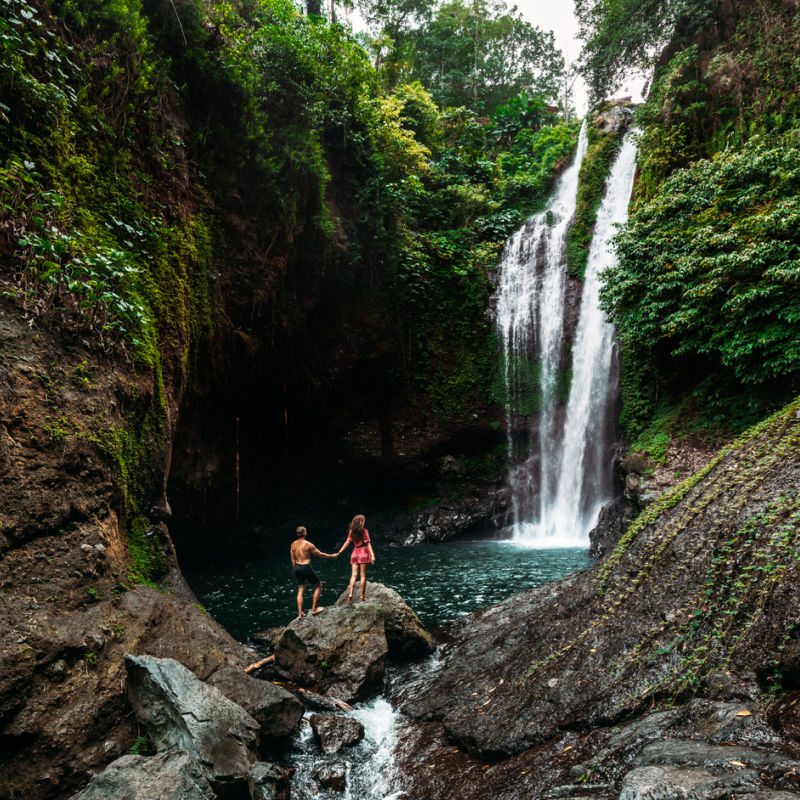 Couple Hold Hands And look UP At Bali Waterfall