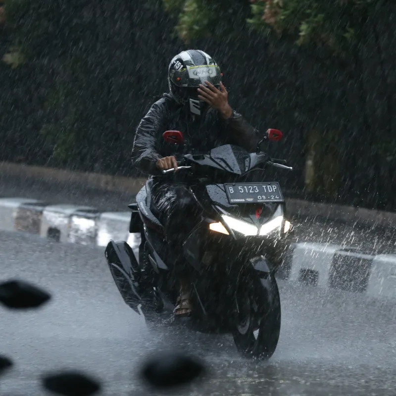 Man Drives Motorbike Moped In Rain In Bali.