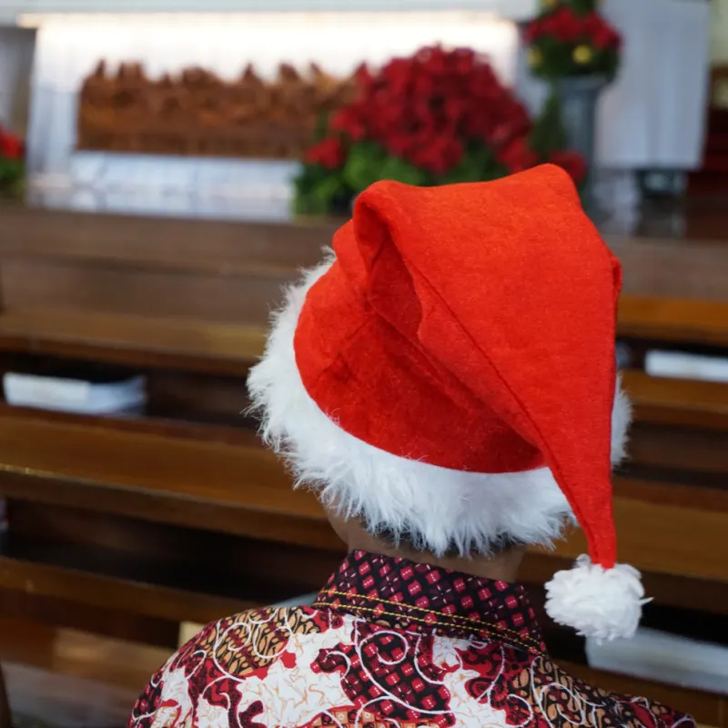 Man Sits in Church In Indonesia Wearing Christmas Hat