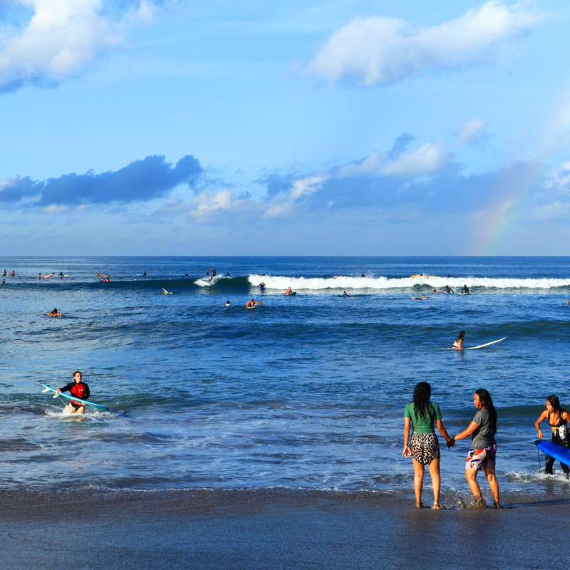 People Surf And Swim At Batu Bolong Beach In Bali