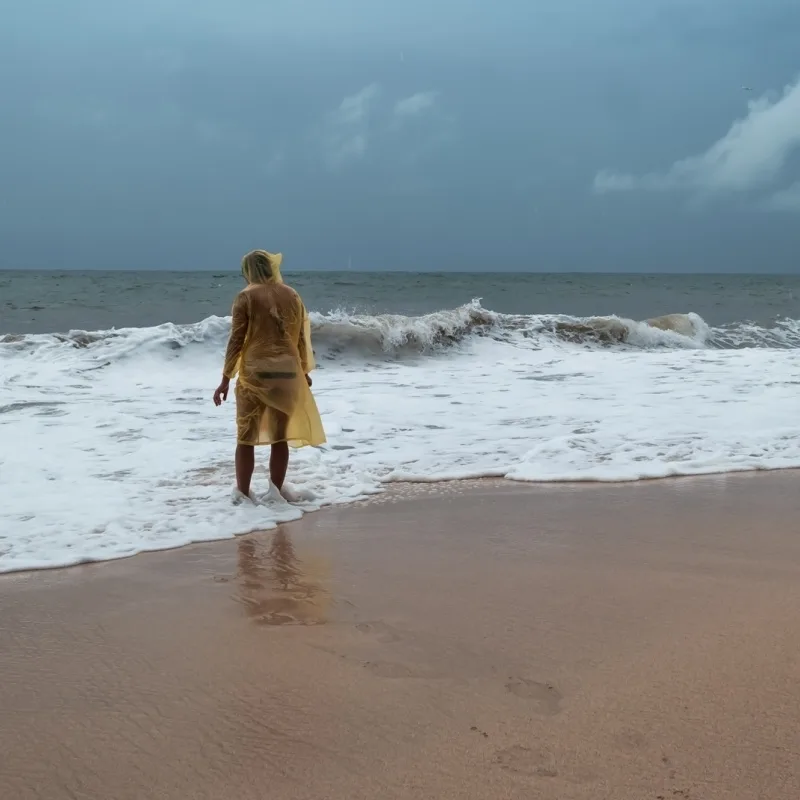 person on a beach in a poncho