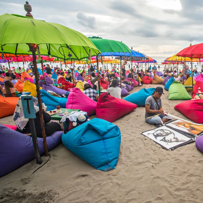 Tourists On Beanbags On Bali Beach.