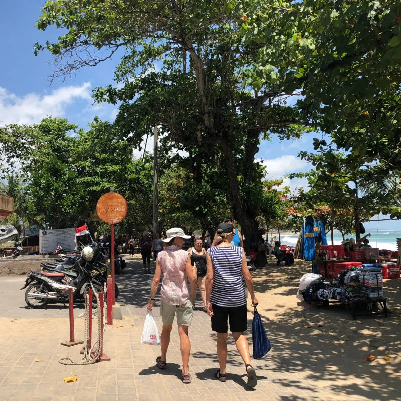 Tourists Walk Past Kuta Beach In Bali