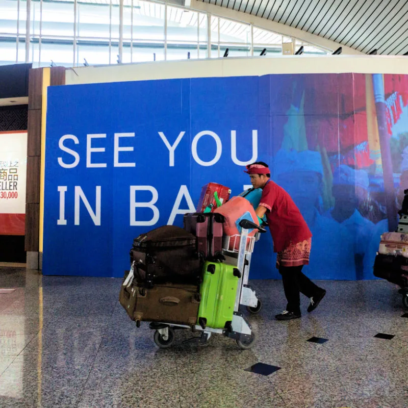 Porter Bandara Mendorong Troli dengan Barang Bawaan