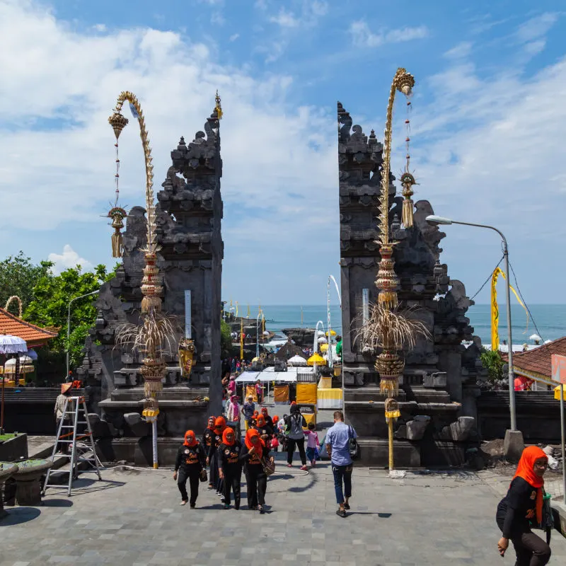 Domestic Tourists Walk Through Temple gateway To Tanah Lot in Bali