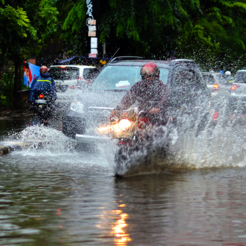 Moped And Cars Drive Through Flood Water After Heavy Rain And Bad Weather IN Bali
