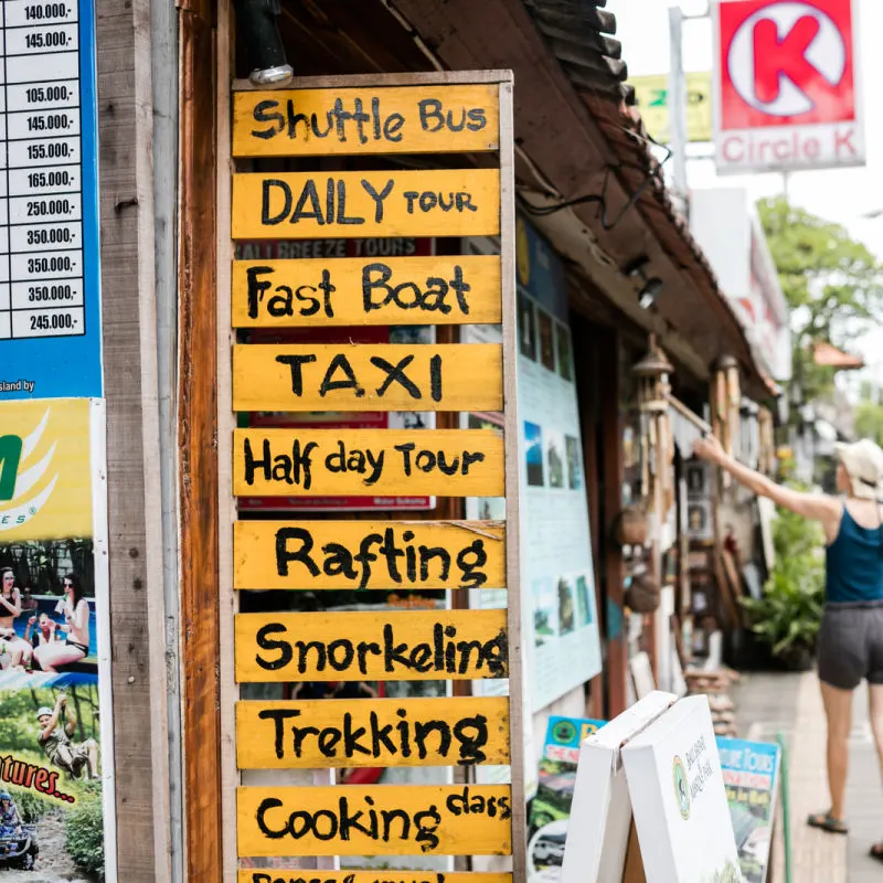 Sign At Tourist Tourism Services Shop Offering Taxi Fast Boat Shuttle Bus and Tours in Bali.