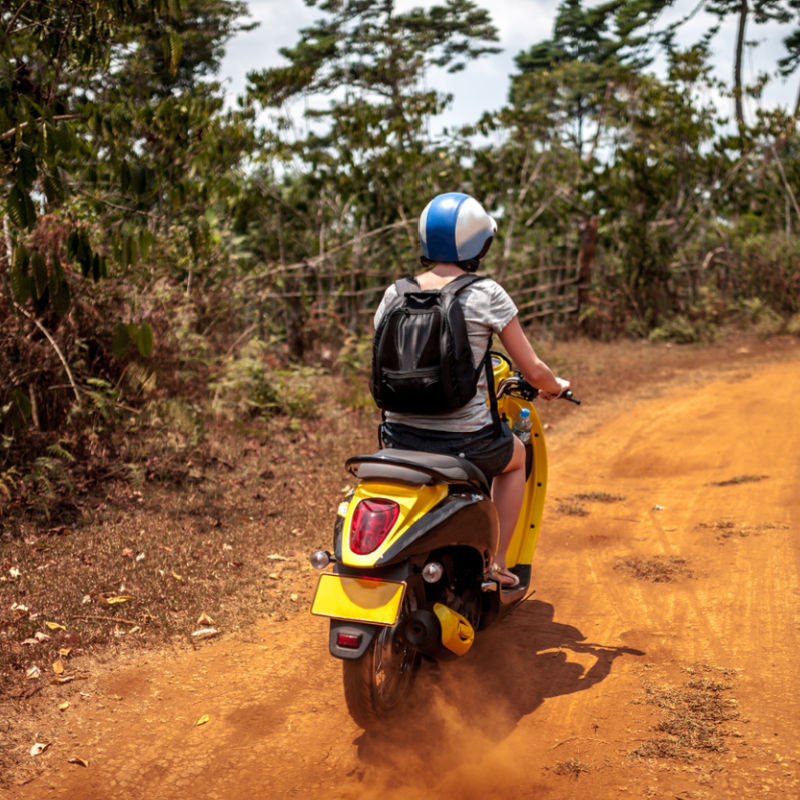 Tourist-Drives-Moped-On-Dirt-Road-in-Bali