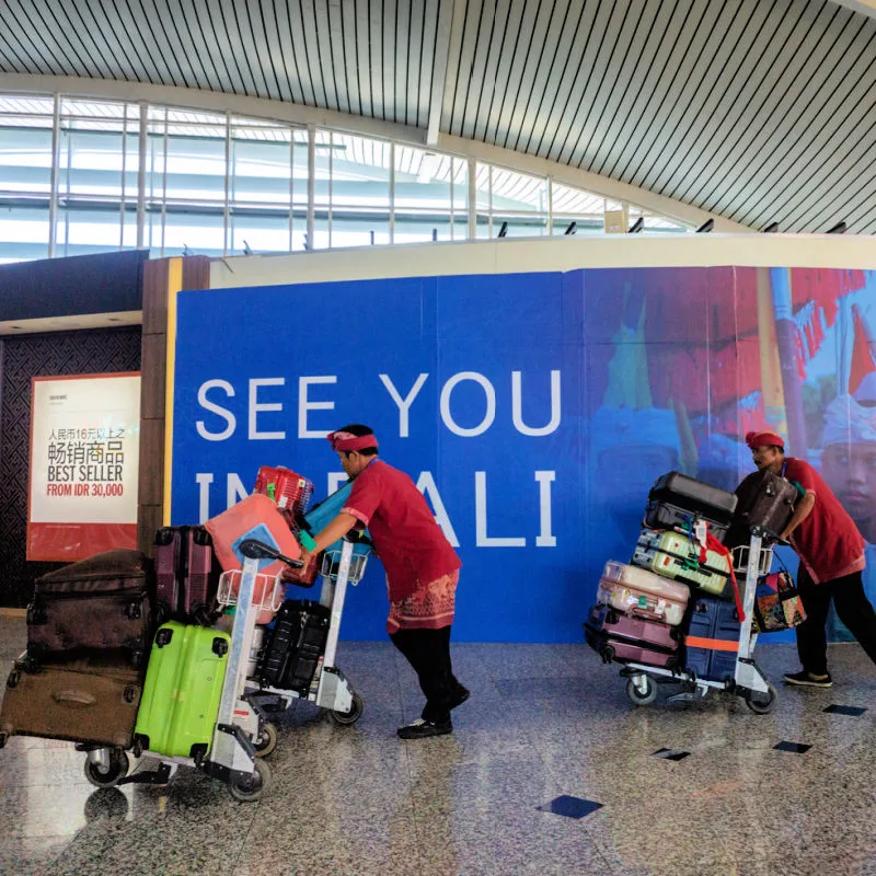 Airport porters push luggage carts at Bali airport