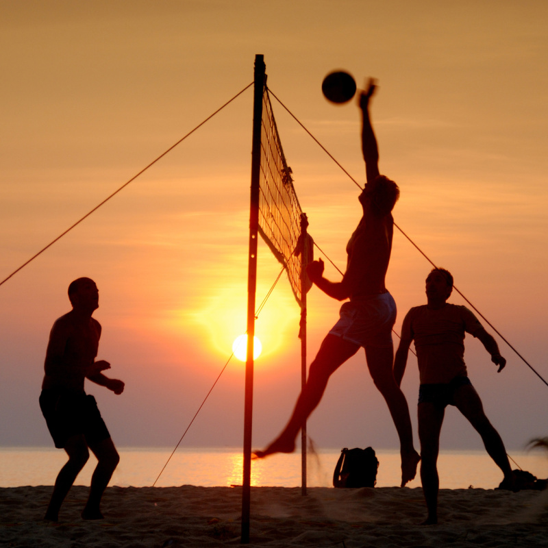 Men-Play-Volleyball-On-Beach-At-Sunset