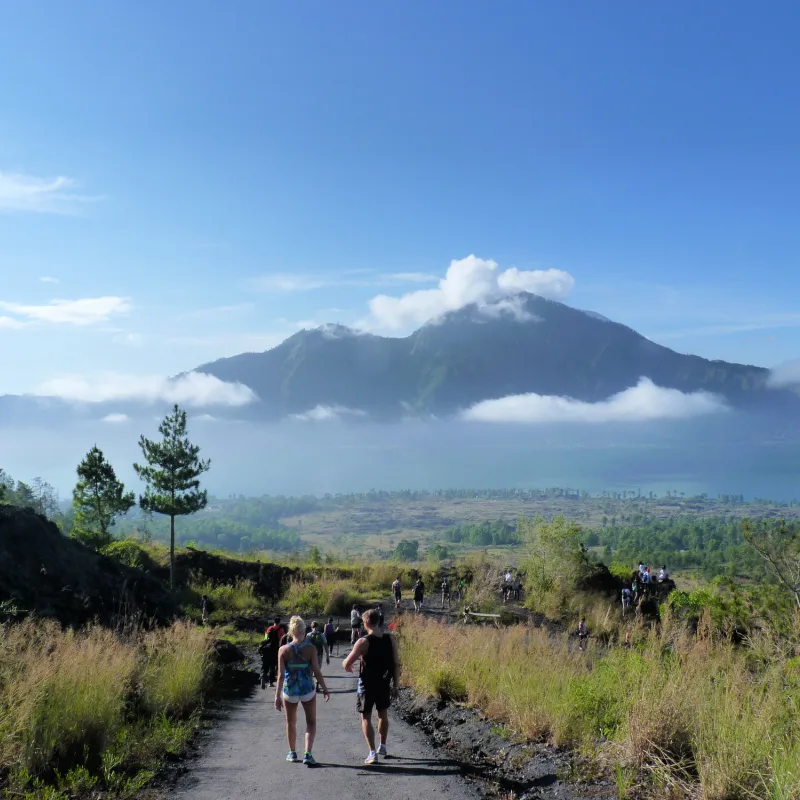 Tourists-Walk-Along-Quiet-Road-In-Bali-Towards-Mount-Batur