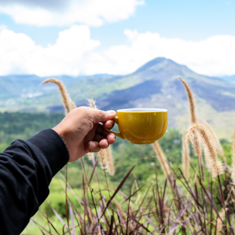 Coffee-Cup-Held-up-in-front-of-Mount-Batur-in-Bali