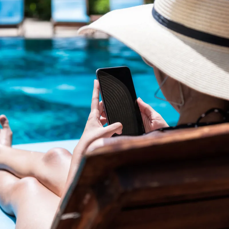 woman looking at phone at pool