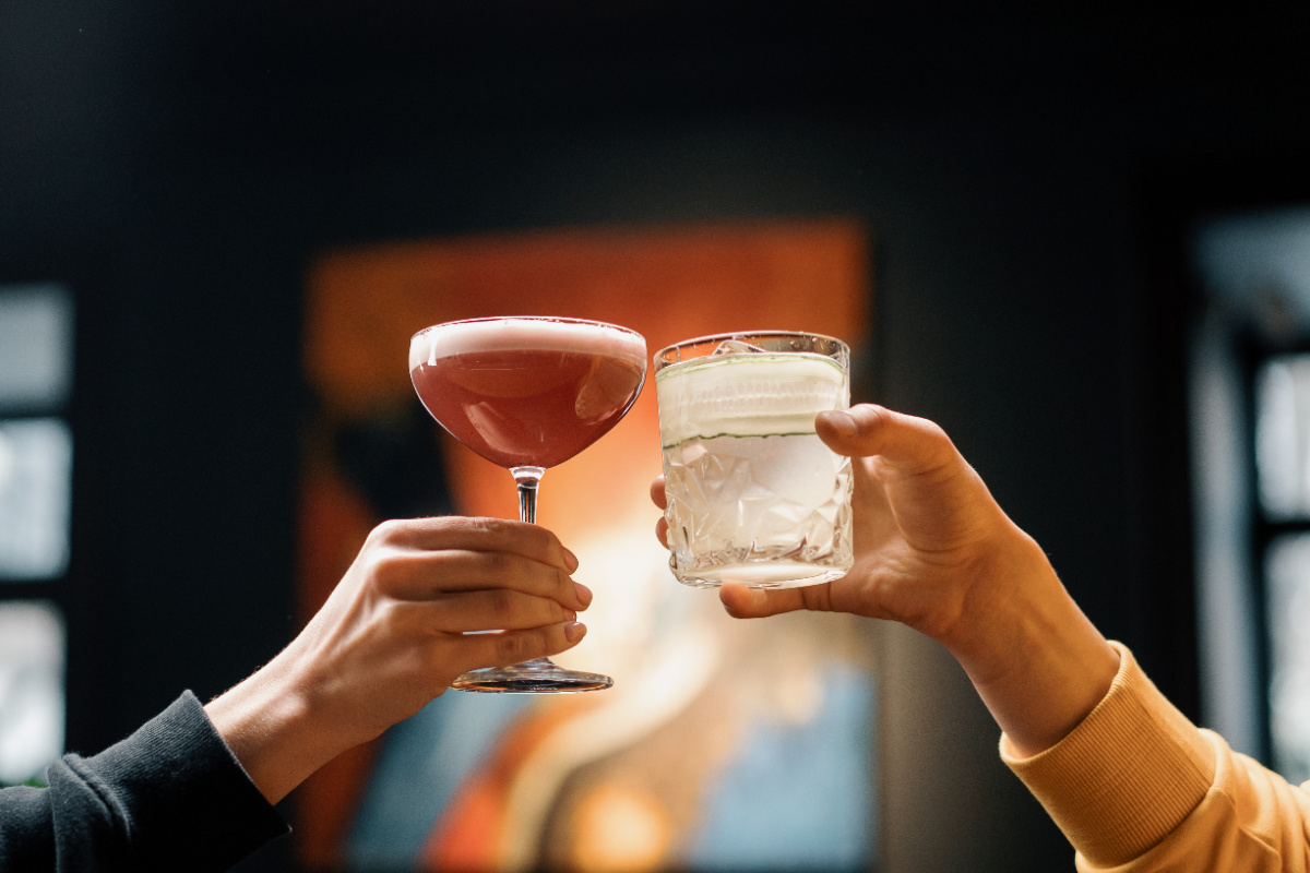 Two People Cheers Cocktails At Bar.jpg
