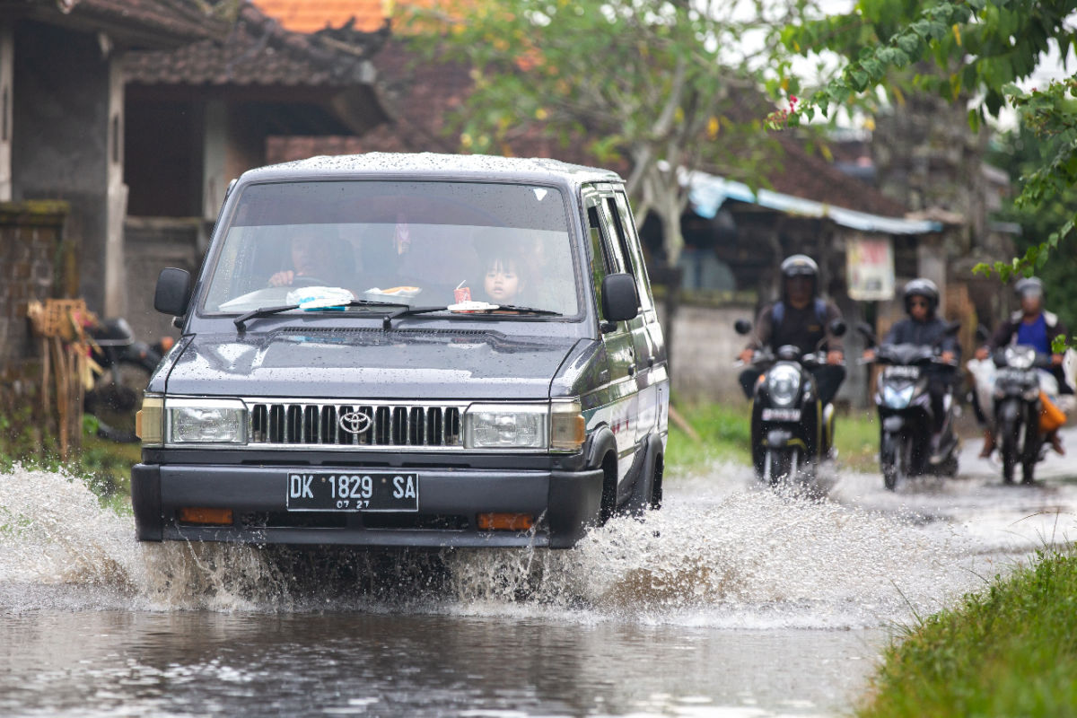 Car drive thorugh flooded road in Bali village in daytime.jpg
