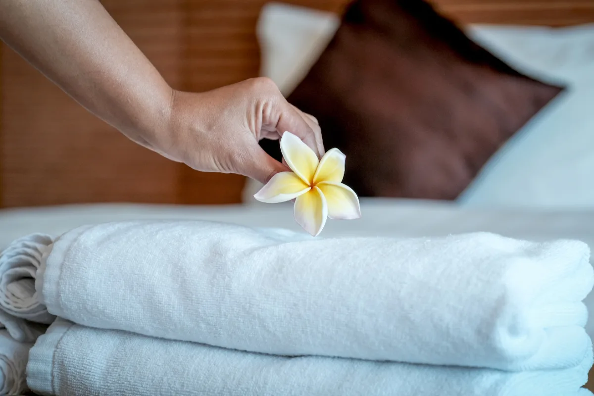 Hotel maid puts flower on towels on hotel bed.jpg