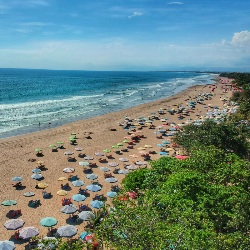 Sunny-beach-in-Bali-with-shade-umbrellas-for-tourists-in-the-daytime