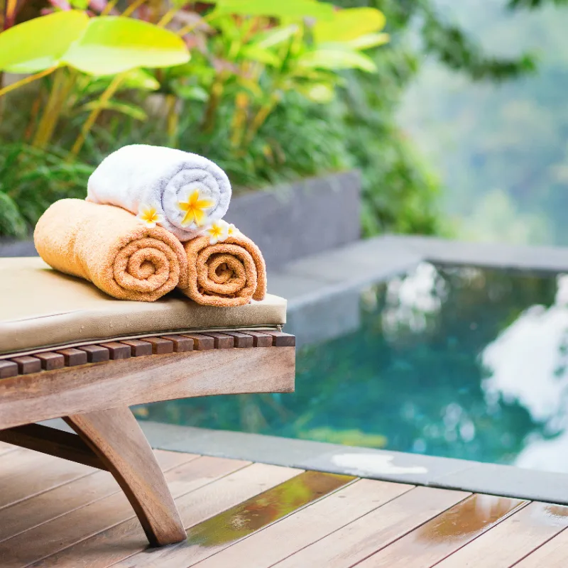 Towels-and-Frangipani-on-Sunlounger-by-Pool-at-Hotel-in-Bali