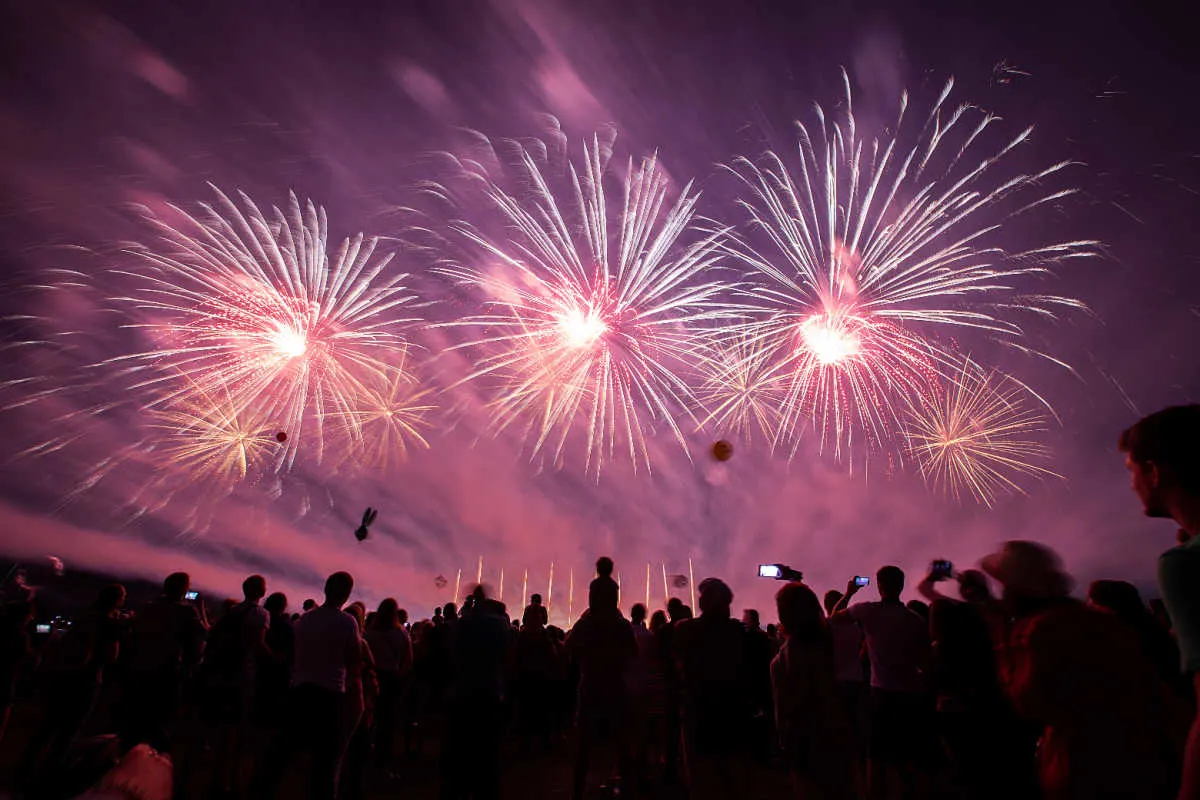 Large crowd watch fireworks at nighttime.jpg