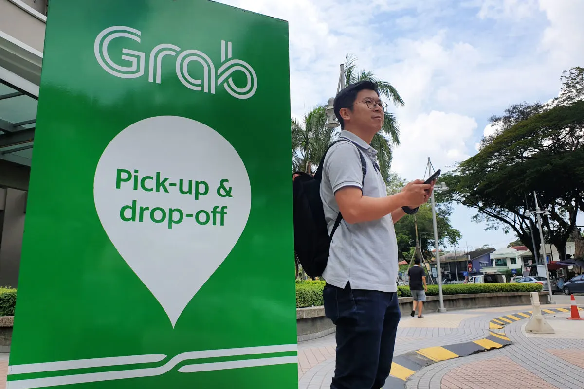 Tourist Stands by Grab Taxi pick up Drop Off Sign.jpg