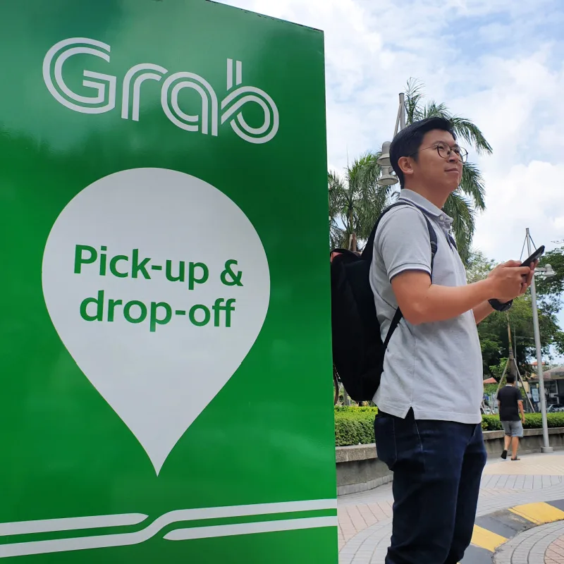 Tourist-Stands-by-Grab-Taxi-pick-up-Drop-Off-Sign