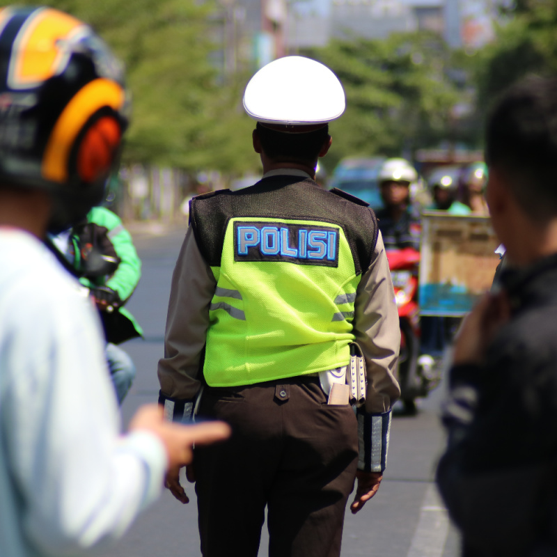 Traffic-Officer-Stands-Looking-at-Cars-and-Bikes-on-Road-in-Bali-