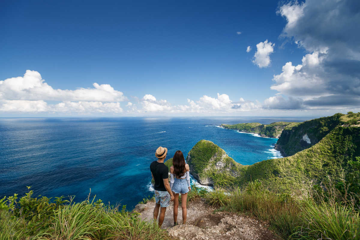 Couple stand on clifftop looking at ocean in Bali.jpg