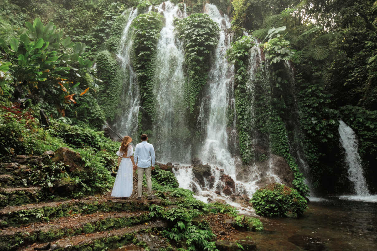 Tourist honeymoon couple stand beneath Bali waterfall in the jungle.jpg