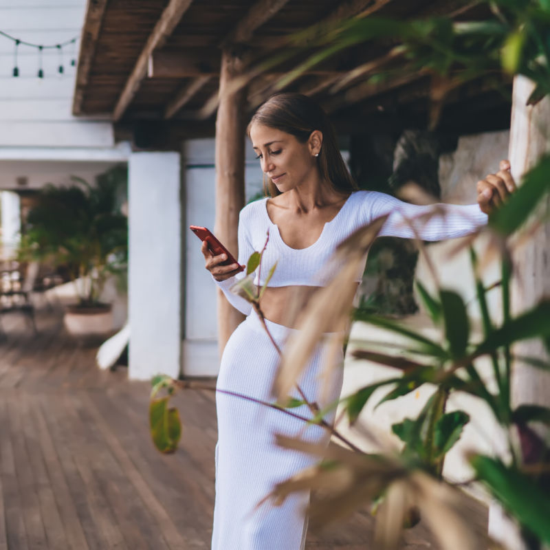 Woman-dressed-in-white-in-Bali-looks-at-her-phone