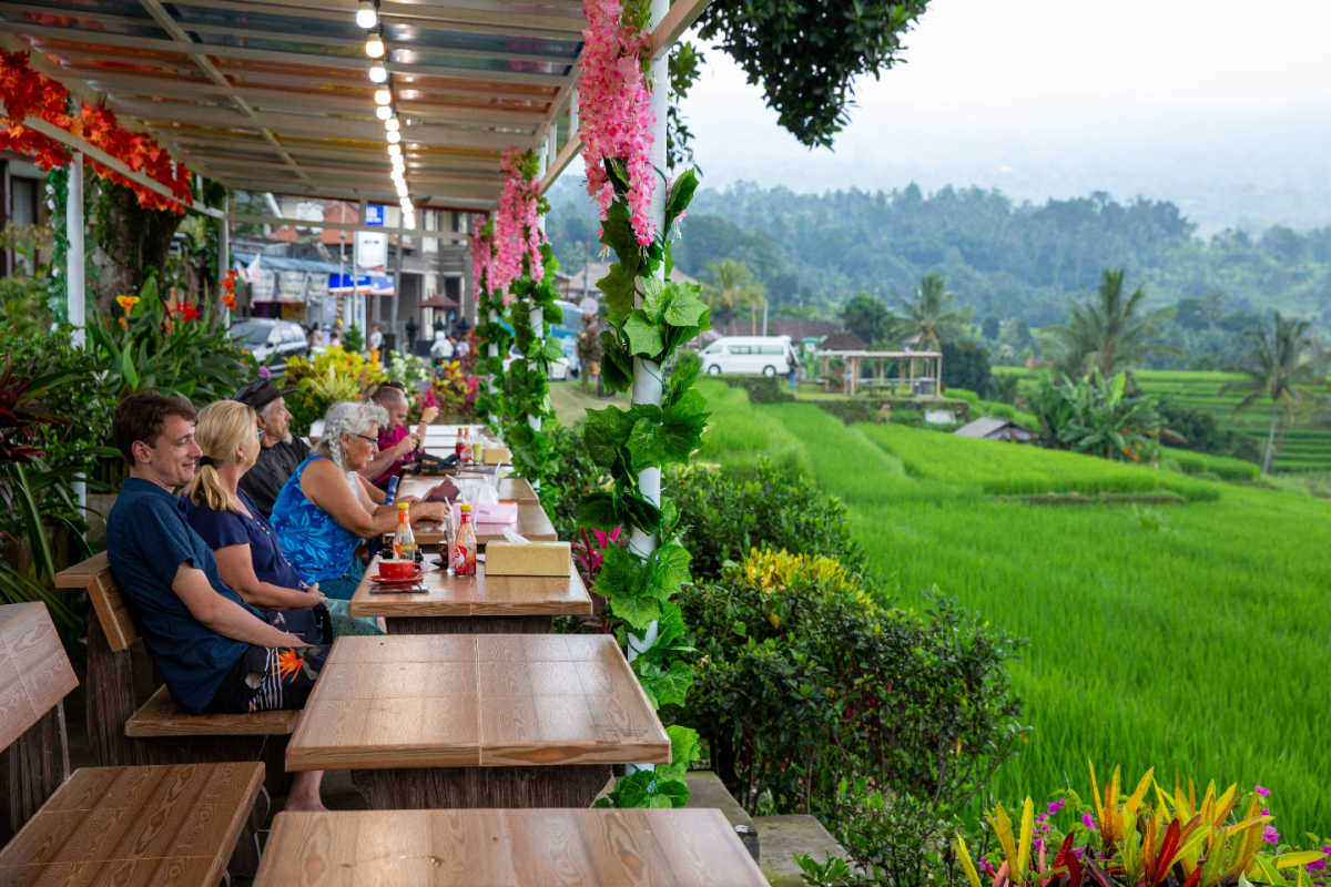 Tourists sit at cafe tables overlooking rice paddies in Bali.jpg
