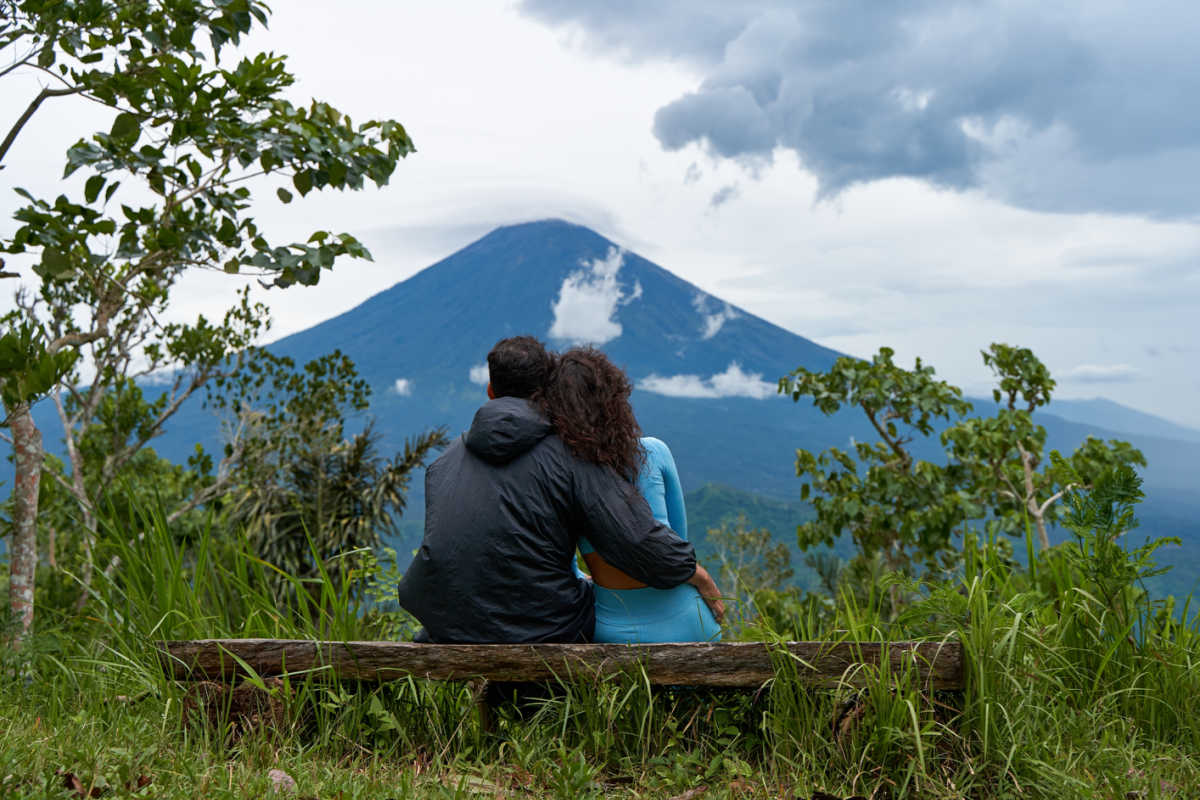 Couple of Hikers Sit On Bench Overlooking Mount Agung in Bali.jpg