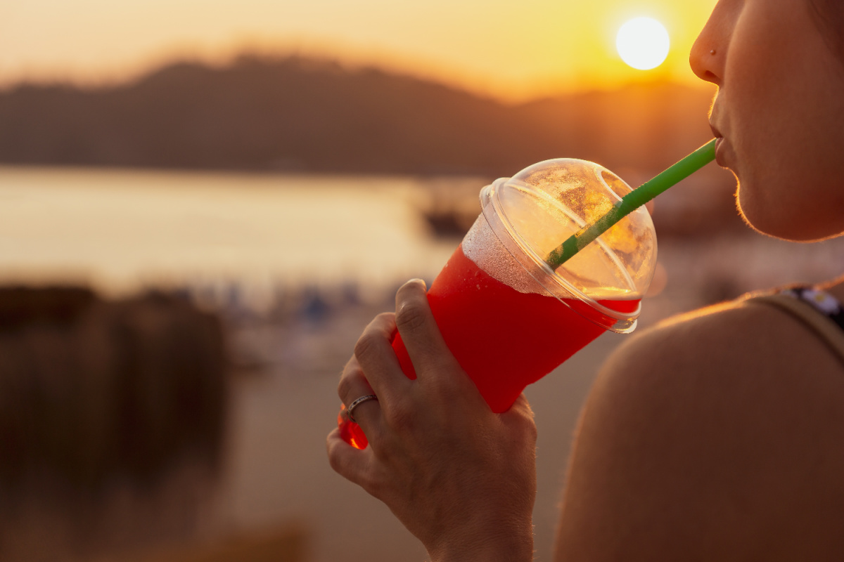 Woman sips on slushy cold dirnk at beach at sunset in Bali.jpg