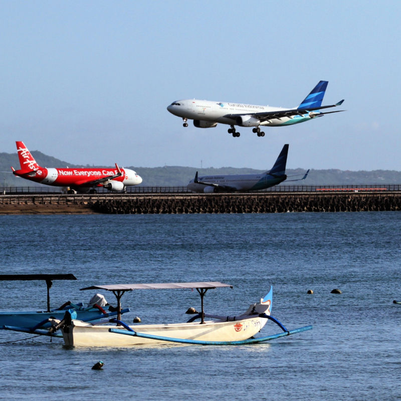 Planes-come-into-land-on-runway-over-ocean-in-Bali