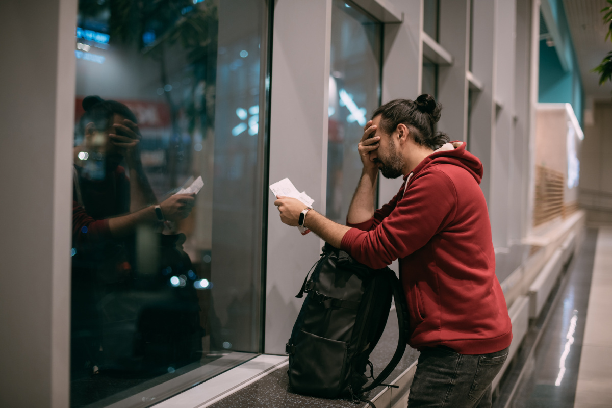 Man Stands At Airport With Head In His Hands.jpg