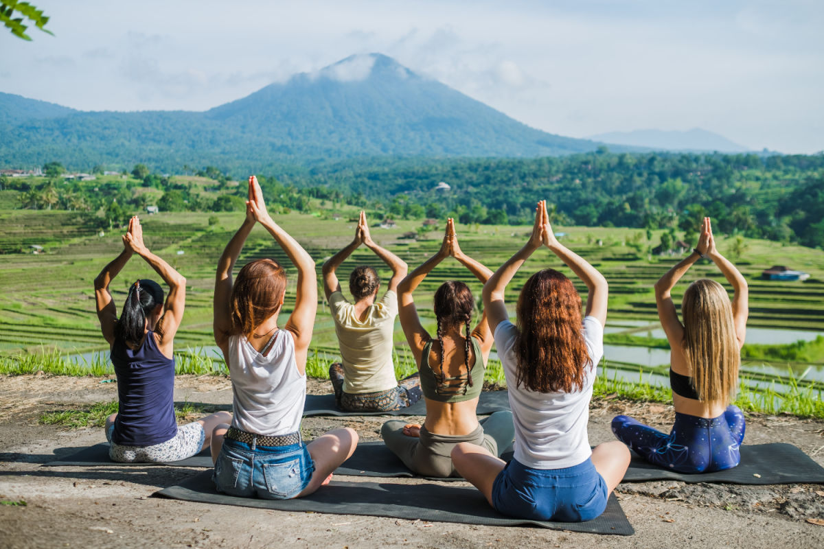 Women Practice Yoga In Bali Looking Over Rice Paddies