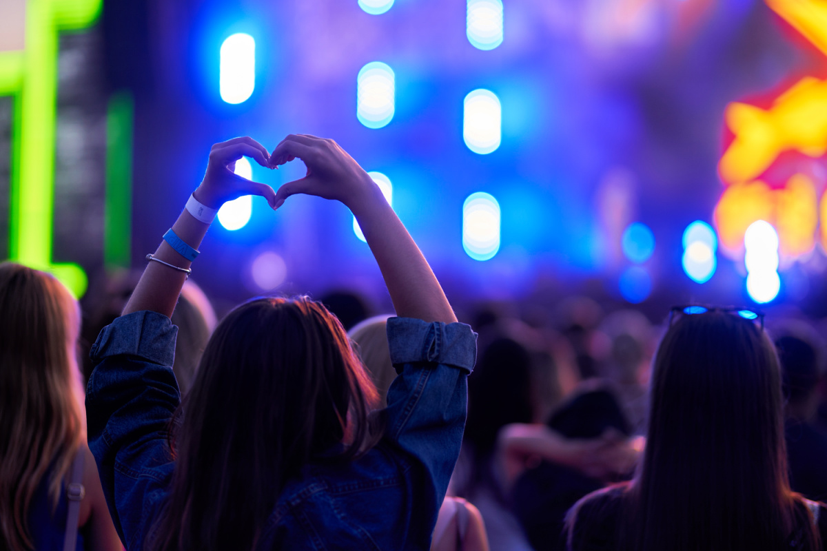 Woman Stands With hands In Heart Shape At Live Msuic Event Festival.jpg