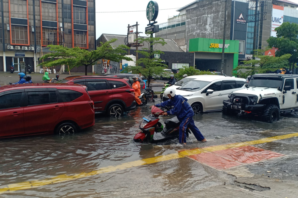 Flooding on city streets in Indonesia with rain on traffic car moped.jpg