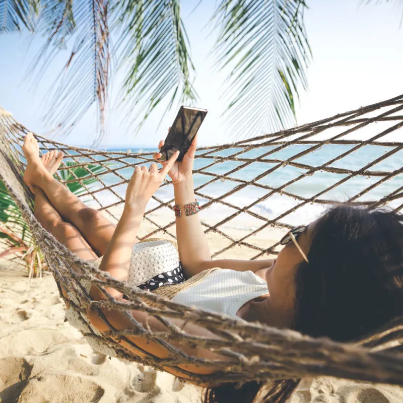 Woman-in-Hammock-on-Beach-with-Phone