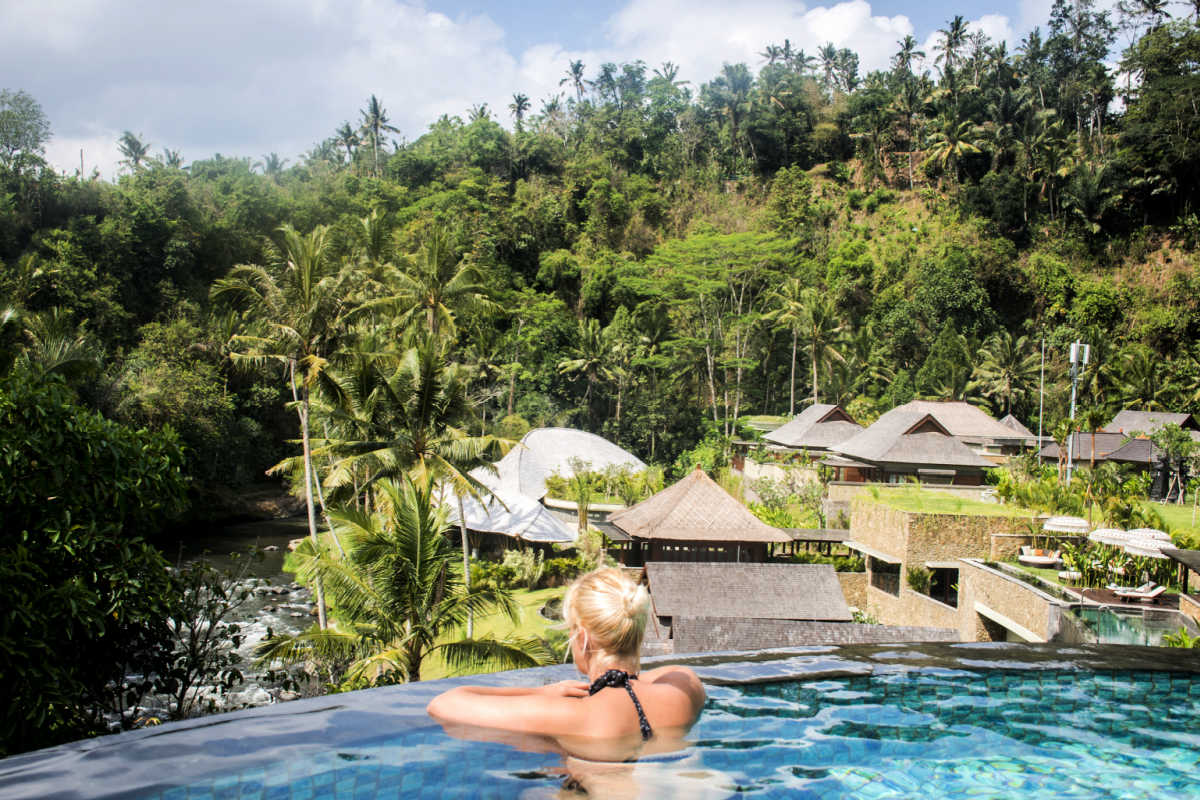 Woman in infinity pool looking out at Bali Ubud jungle at hotel