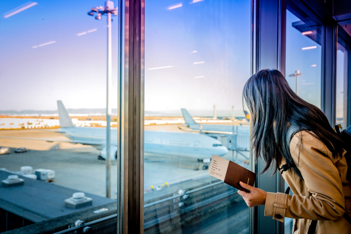 Woman looks at plane with passport in her hand at airport .jpg