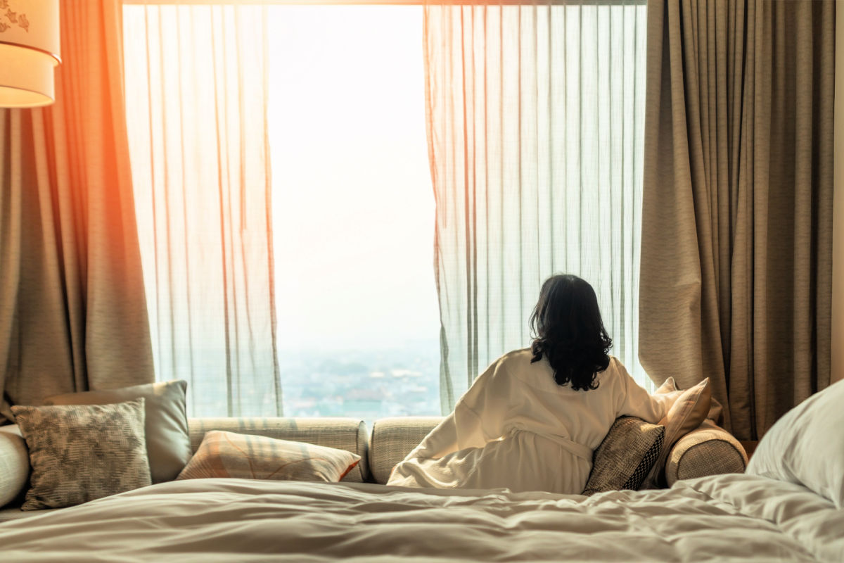 Woman Looks OUt Window Of Luxury Hotel Room Bali Ocean View.jpg